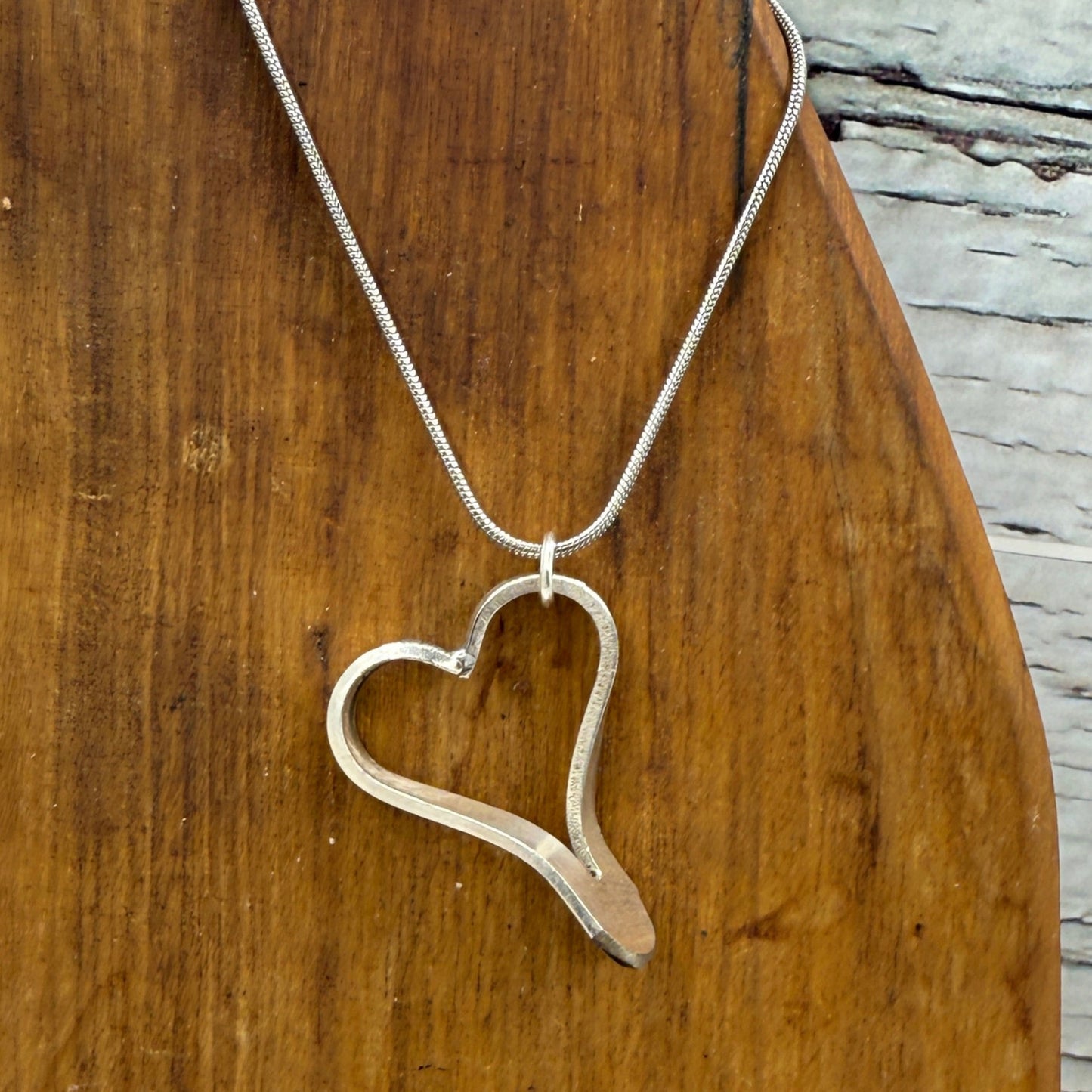 Wooden cutting board with a metal heart-shaped object on a rustic wooden surface