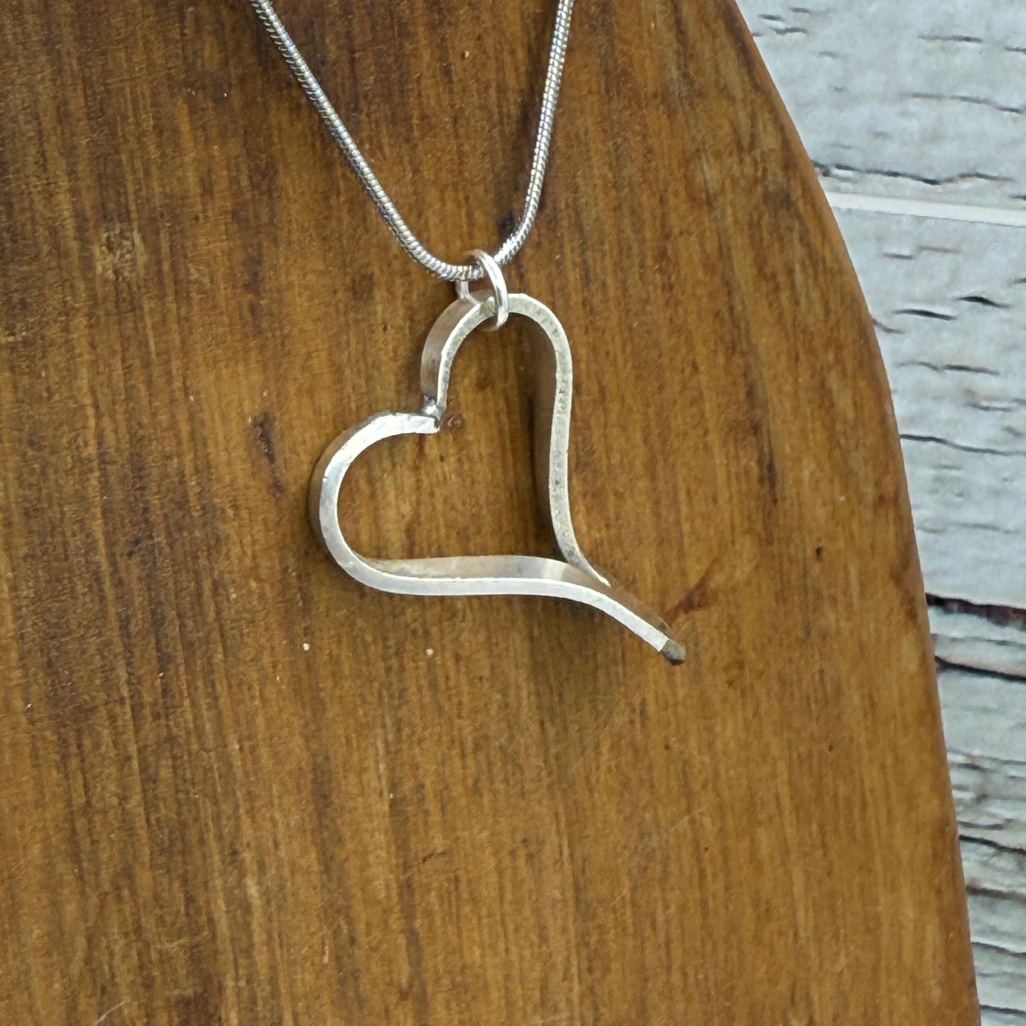 Silver necklace with a heart-shaped clasp on a wooden surface